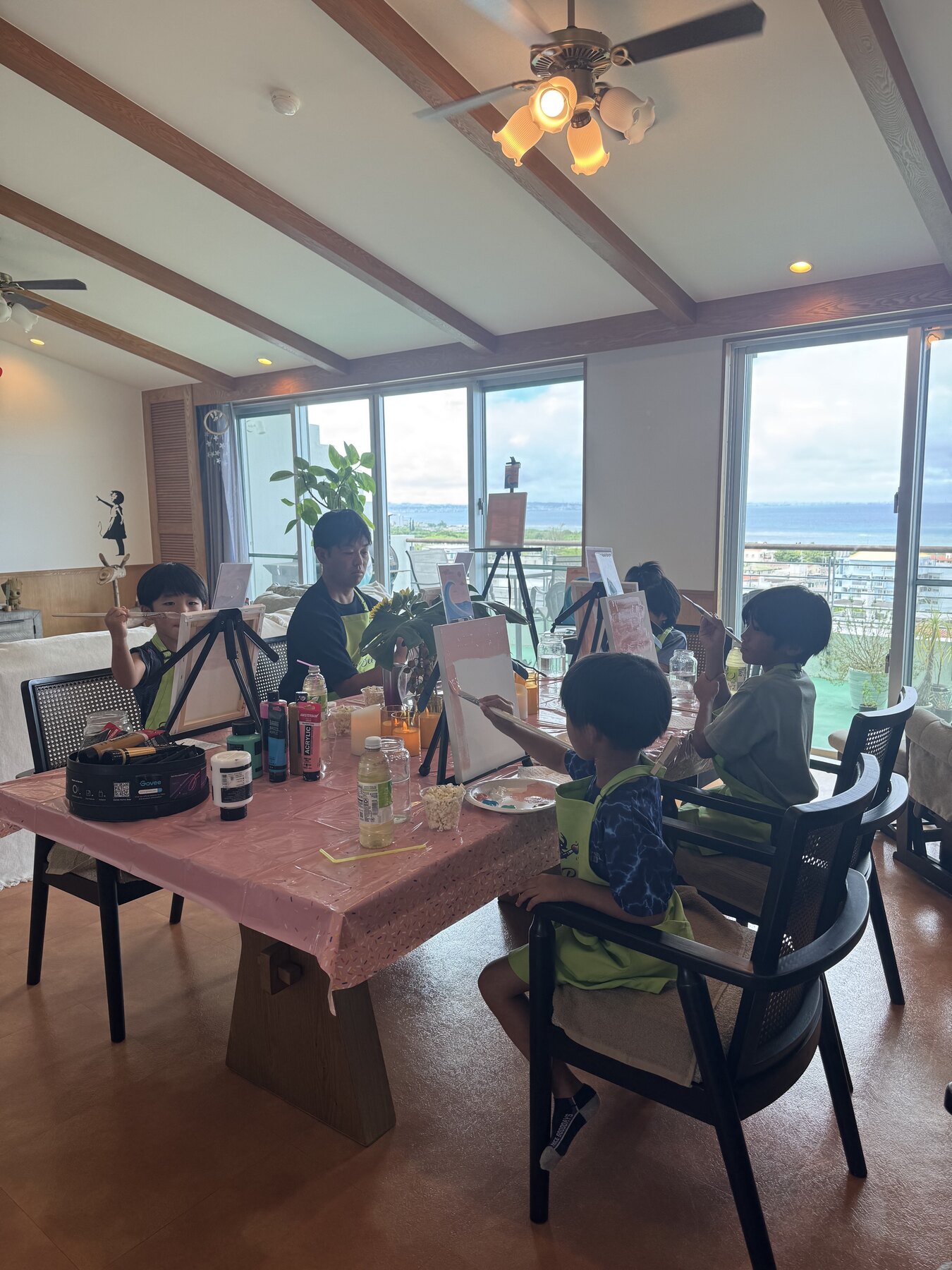 Pinto Beetle family painting pink wave canvases around the ocean-view studio table