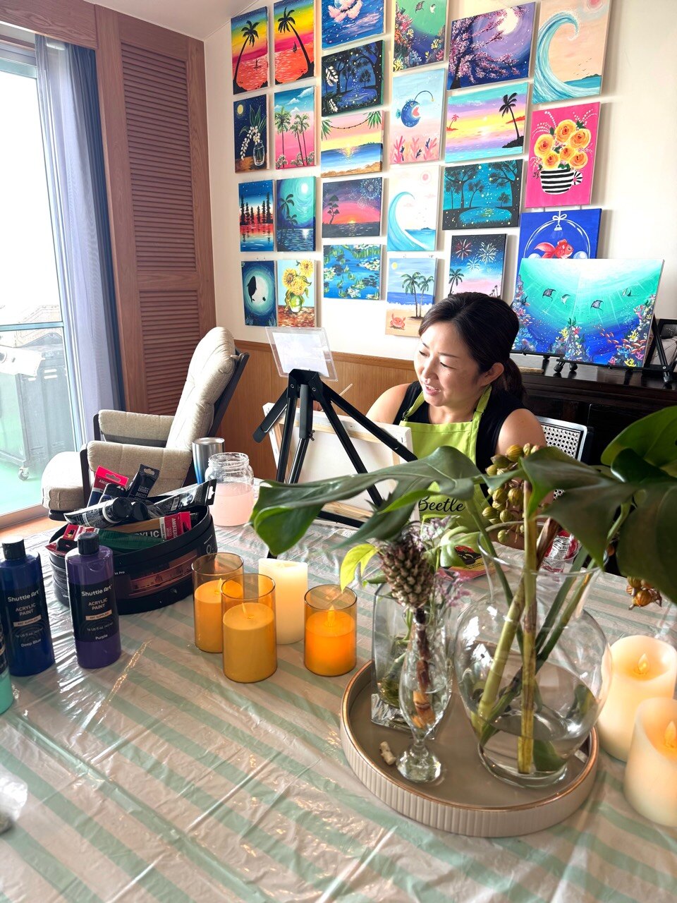 Pinto Beetle guest painting beside candles in the ocean-view studio