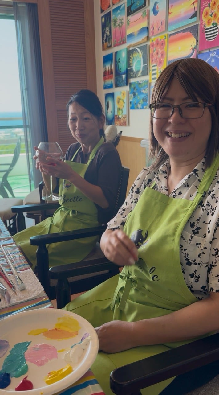 Two Pinto Beetle guests smiling together during a tropical sunset painting class