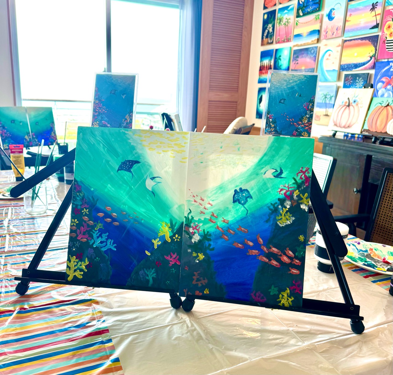 Finished Under the Sea pair paintings displayed on easels in the Pinto Beetle ocean-view studio