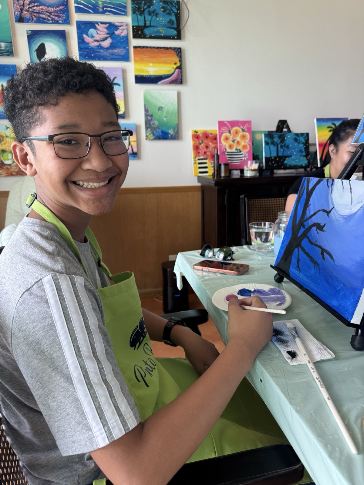 Young Pinto Beetle guest smiling while painting a blue night scene